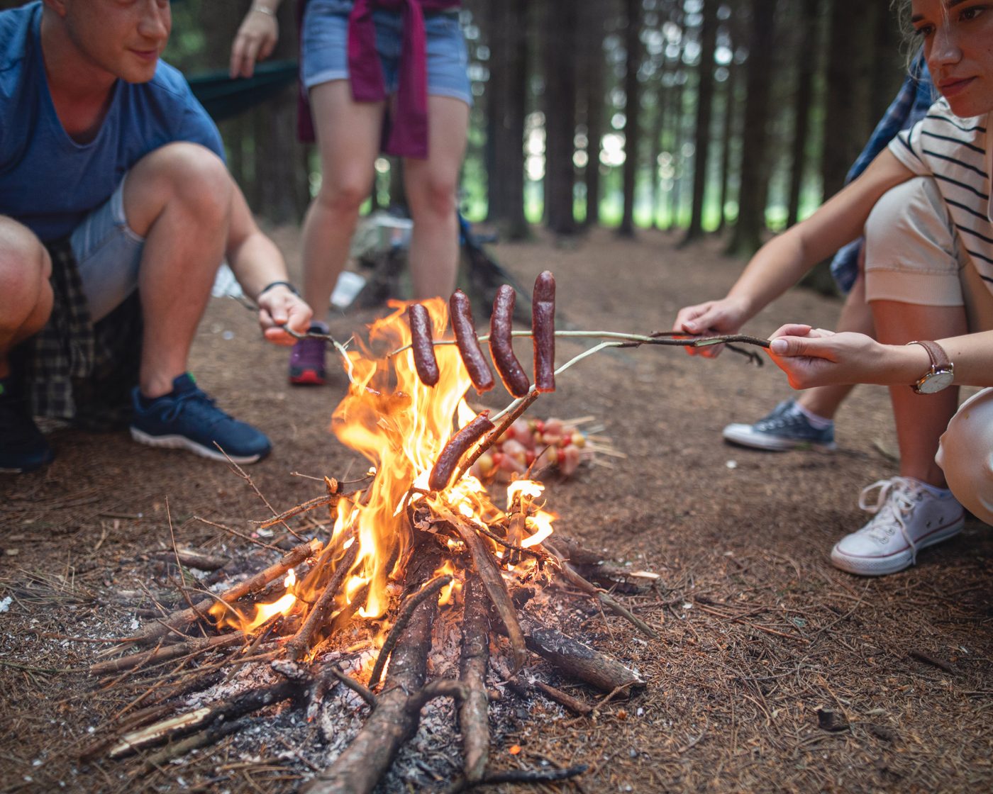 Campers roasting hot dogs at campfire